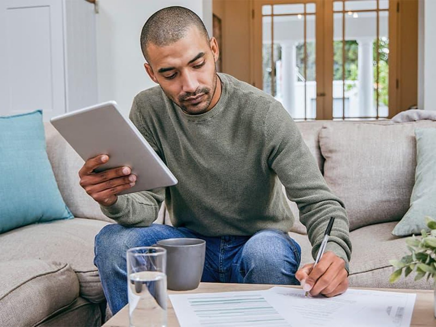 A man sitting on the couch writing papers.