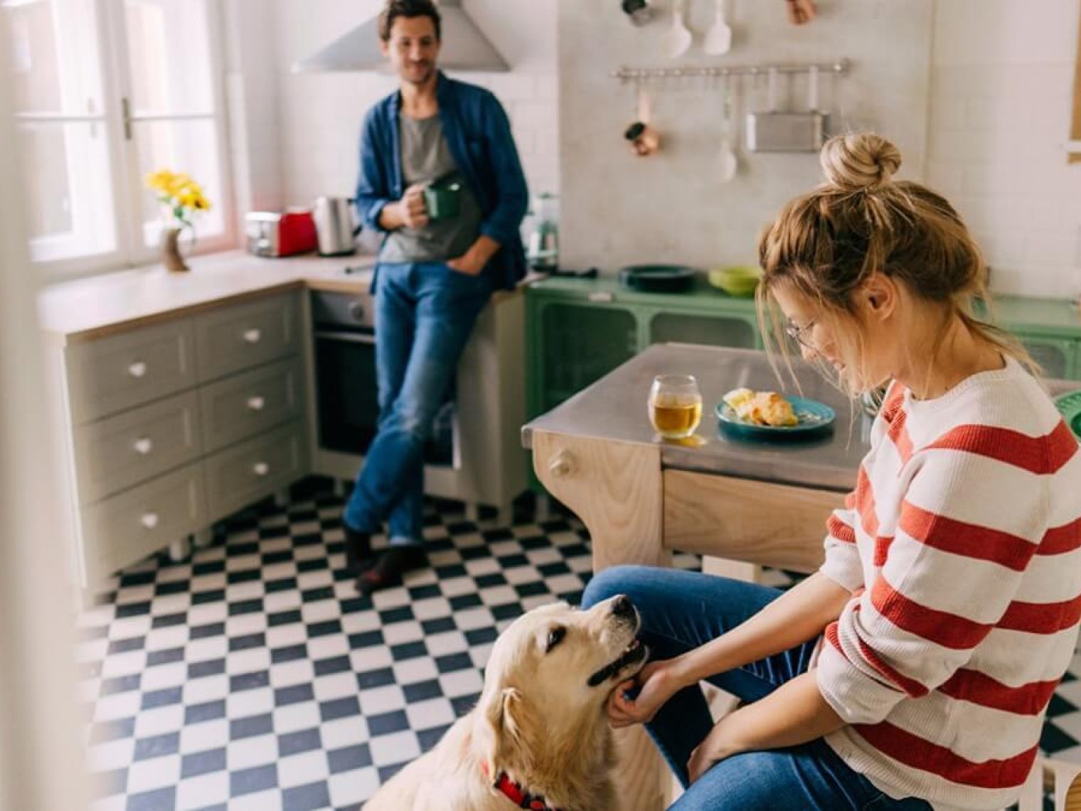 A couple in their kitchen with a dog.