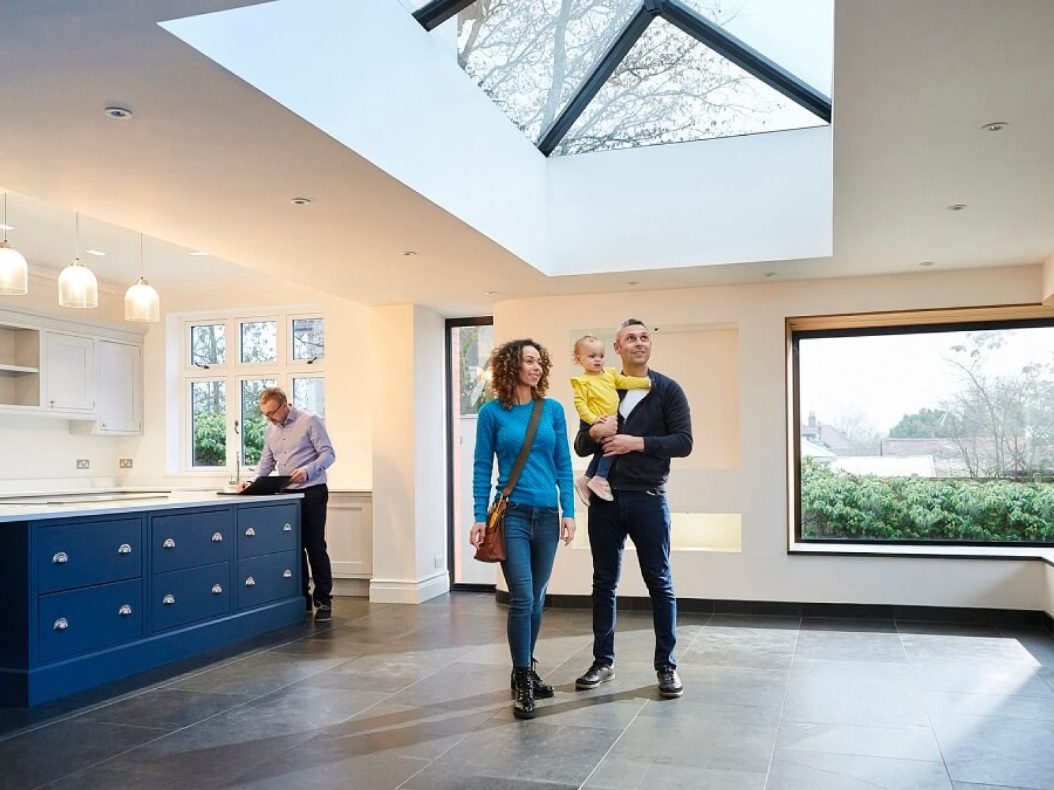 Family admires the interior of a home for sale while their real estate agent prepares documents.