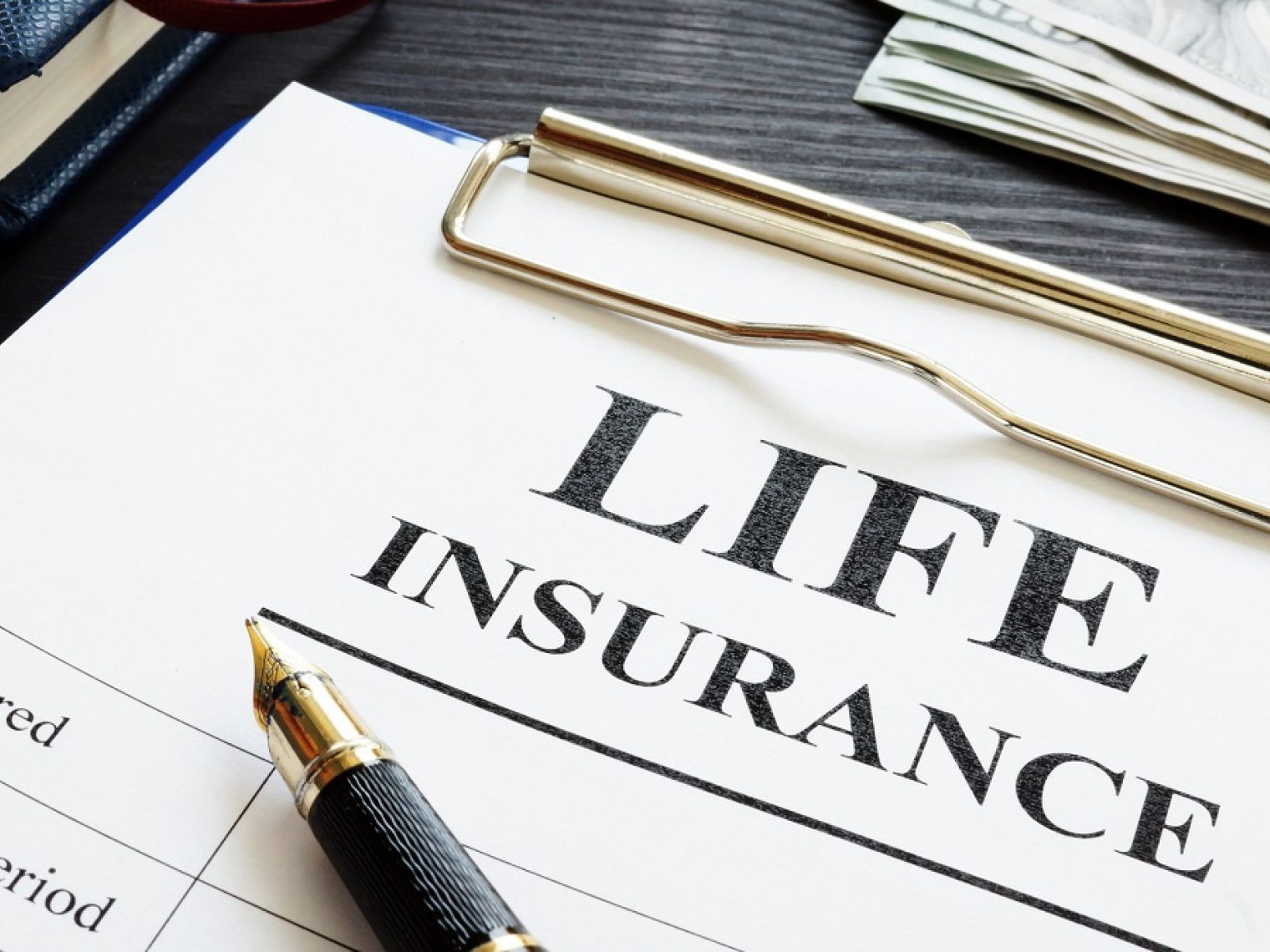 Life insurance papers on a clipboard underneath a pen.