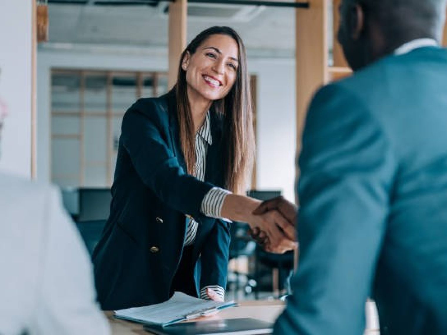 Real estate agent woman shakes hands with man facing away from camera