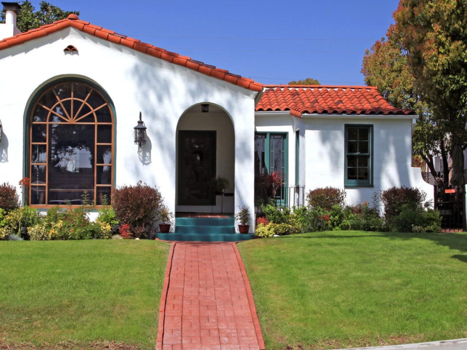 Front view of a Spanish style home with a clay tile roof and white walls.