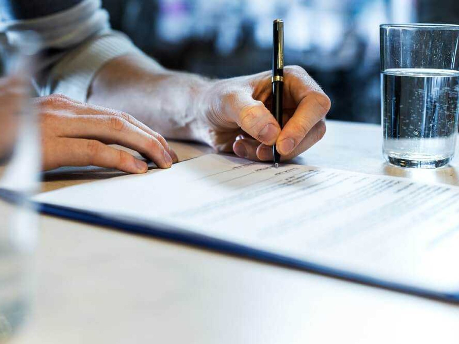 Close up of a man's hands signing a document.